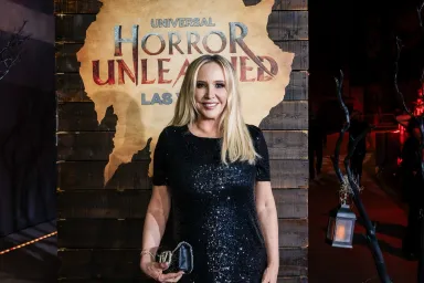 Shannon Beador in a black dress standing in front of a sign that says, "Horror Unleashed"