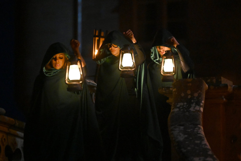 Candiace Dillard Bassett, Lisa Rinna, and Rob Rausch on The Triators, wearing green cloaks and carrying lamps 